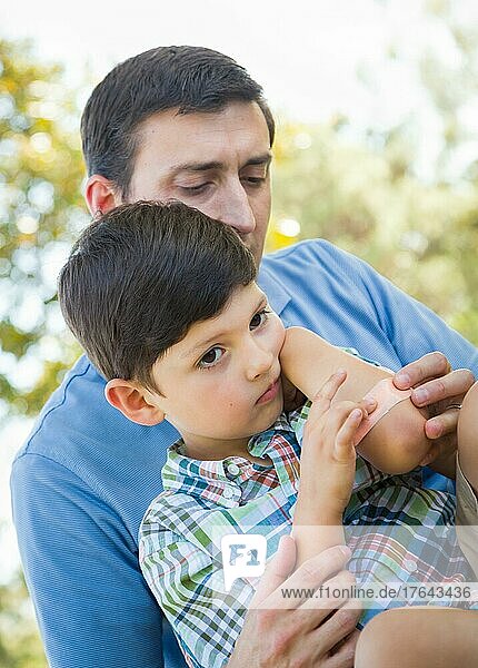 Loving father puts a bandage on the elbow of his young son in the park