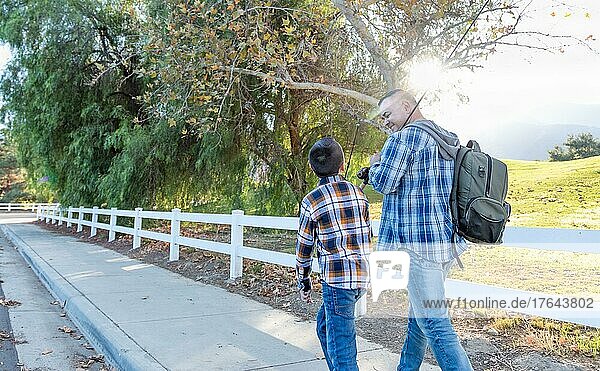 Gemischtrassiger Vater und Sohn  die mit Angelruten im Freien spazieren gehen