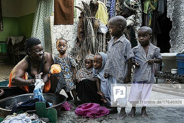 Frau mit Wäsche in Plastikschüssel  viele Kinder  Innenhof  Paje  Ostküste  Unguja  Sansibar  Tansania  Afrika