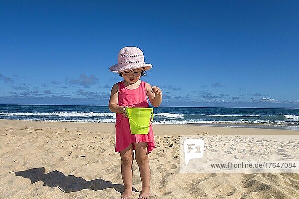 Toddler girl holding a green bucket at the beach  Kauai island  Hawaii