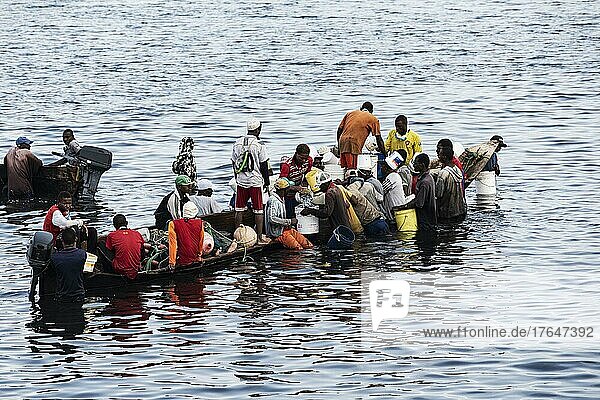 Fischer und Fischhändler an kleinem Boot im Wasser  Fischereihafen  Fischerboot  Stone Town  Unguja  Sansibar  Tansania  Afrika