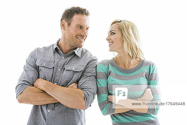 Studio shot of smiling couple with arms crossed