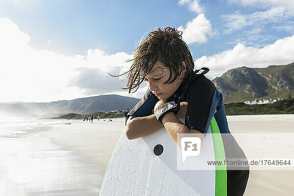South Africa  Hermanus  Boy (8-9) resting on his surfboard