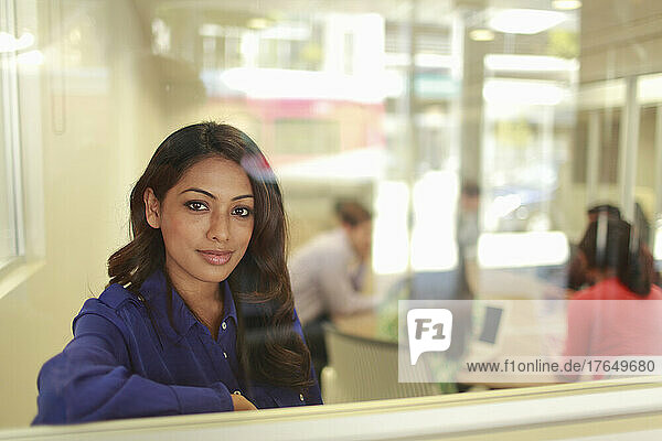 Portrait of young woman behind office glass