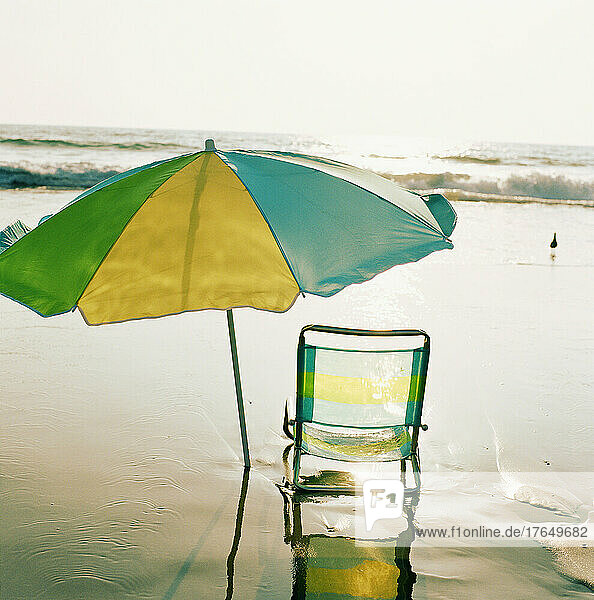 Beach chair and umbrella on beach at sunset