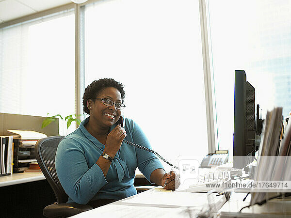 Businesswoman sitting at desk using telephone