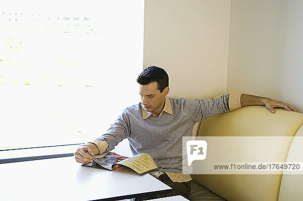 Businessman reading magazine in cafeteria