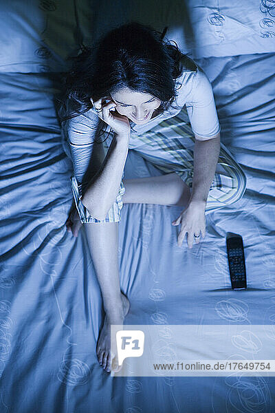 Woman sitting on bed using mobile phone