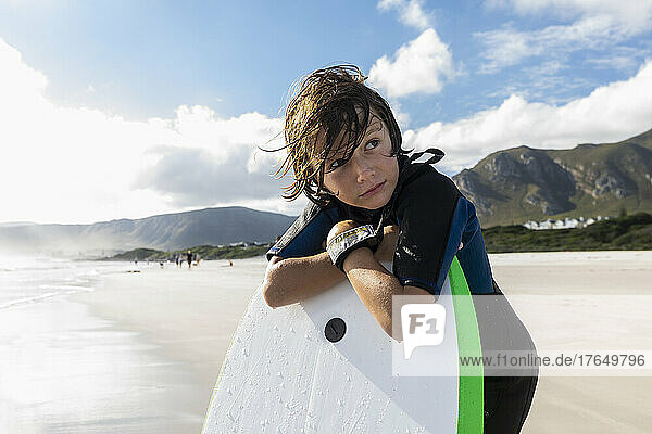 South Africa  Hermanus  Boy (8-9) resting on his surfboard