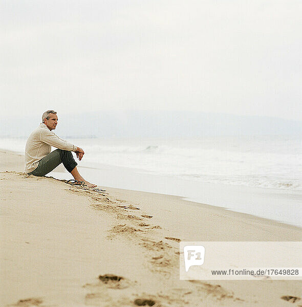 Man sitting on beach looking at ocean