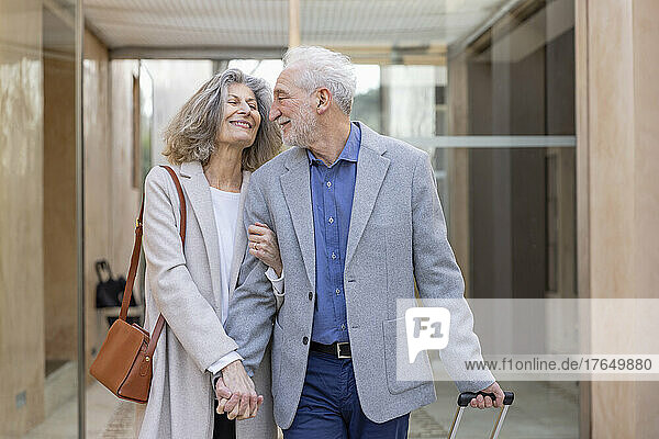 Smiling senior couple holding hands in lobby at boutique hotel