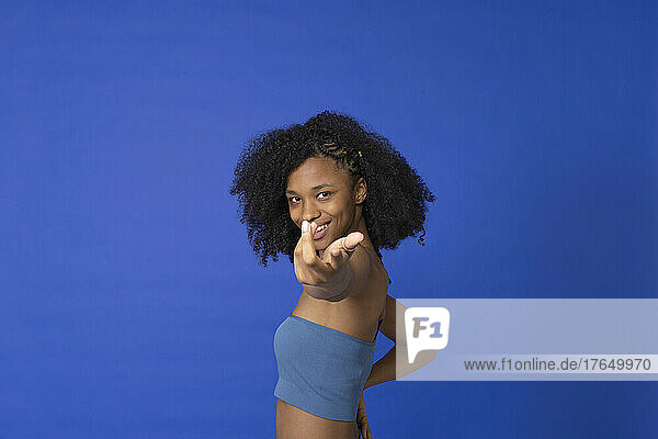 Smiling woman gesturing hand against blue background