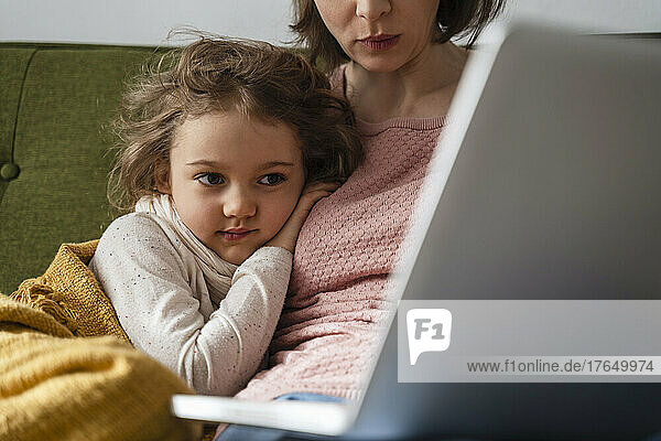 Mother with sick daughter using laptop at home
