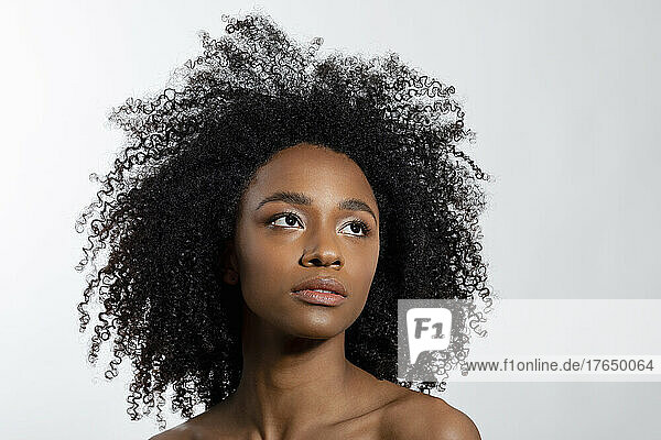 Thoughtful young woman with curly hair against white background