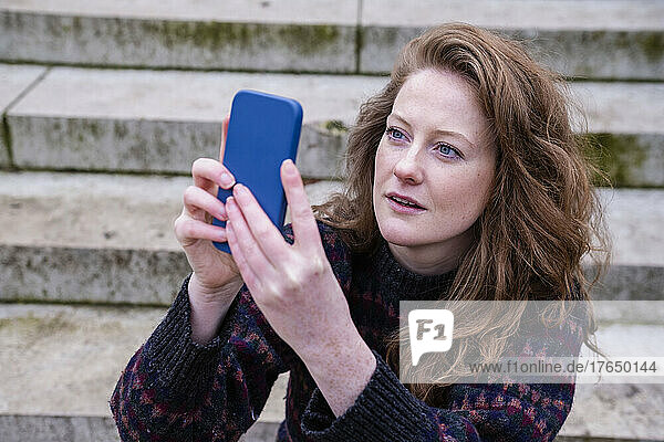 Young woman using smart phone sitting on steps