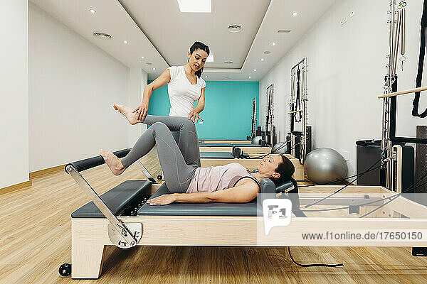 Instructor teaching woman pilates exercise on reformer machine