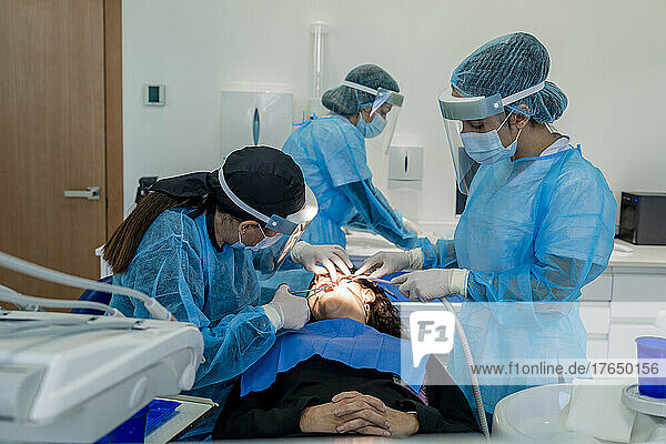 Surgeon with nurses doing surgery of patient in operating room at hospital