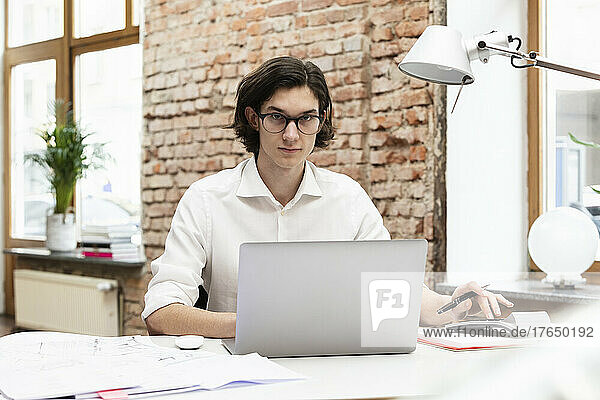 Geschäftsmann mit Laptop sitzt am Schreibtisch im Büro