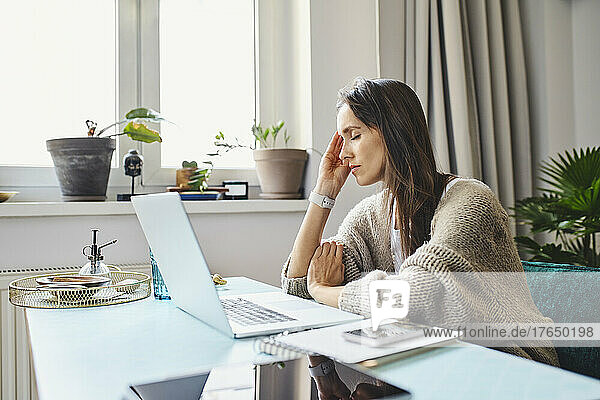 Freelancer with eyes closed sitting at desk