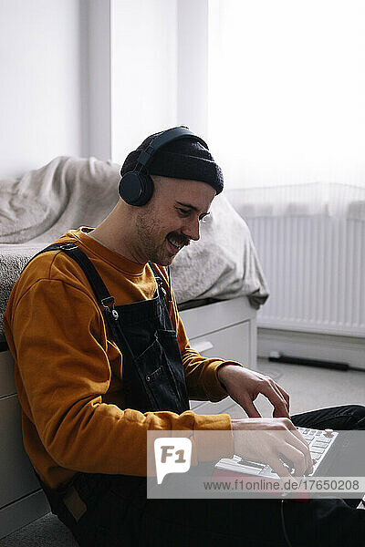 Man wearing headphones using piano at home
