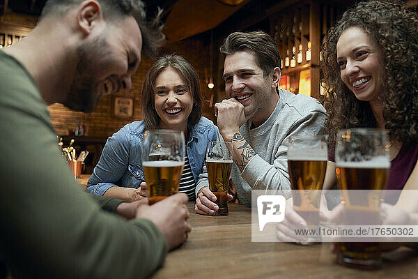 Group of happy friends having beer and socializing in a pub