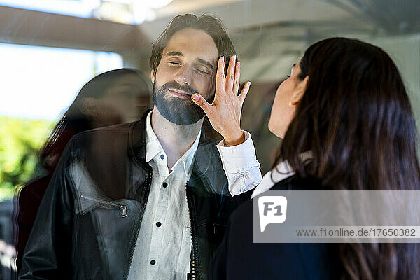 Woman touching man separated through glass pane
