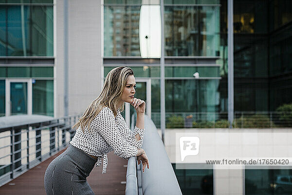 Businesswoman leaning on railing on office balcony