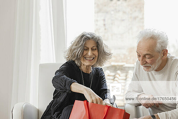 Glückliches Seniorenpaar mit Einkaufstüten sitzt am Fenster eines Boutique-Hotels