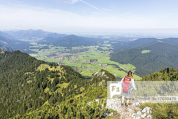 Woman wearing backpack standing with hiking pole in the mountains