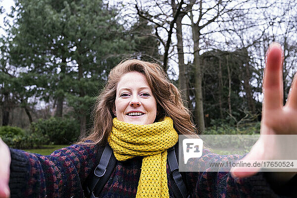 Glückliche junge Frau mit gelbem Schal genießt den Wald