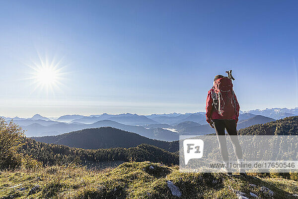 Female hiker admiring Bavarian Prealps at foggy sunrise