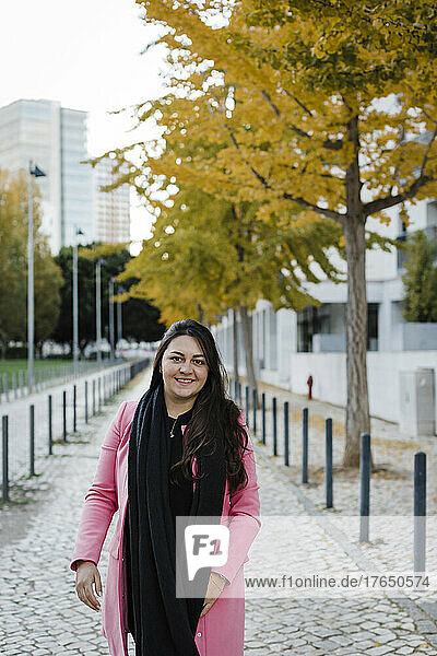 Smiling woman standing on sidewalk in public park