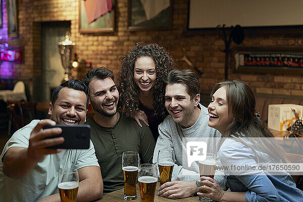 Gruppe glücklicher Freunde  die Bier trinken und ein Selfie in einer Kneipe machen