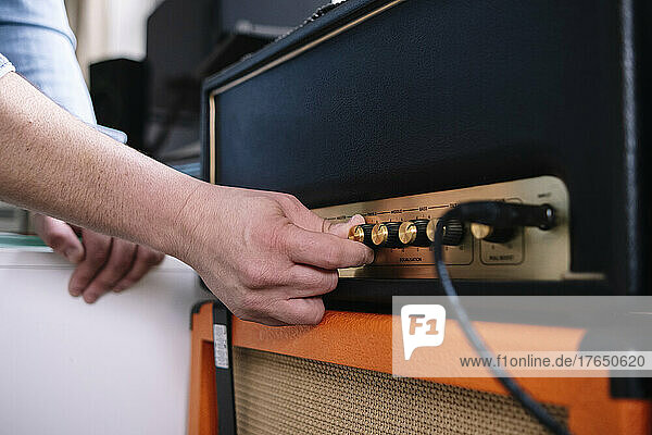 Hands of man using amplifier in home studio