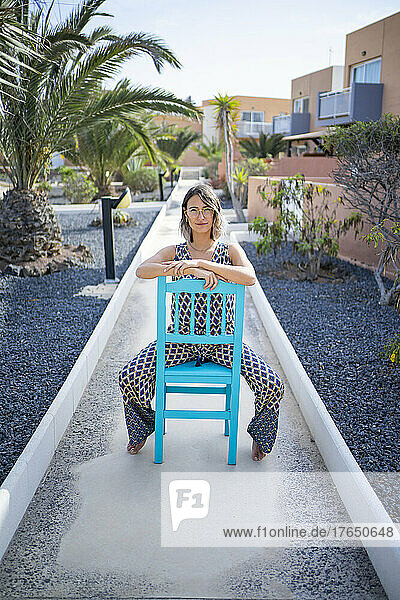 Junge Frau sitzt auf blauem Stuhl auf Fußweg