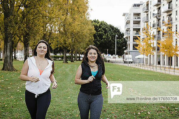 Happy sisters jogging in public park