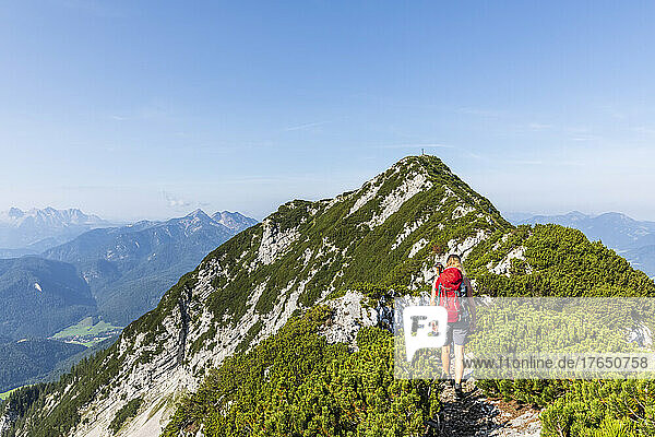 Woman with backpack walking on mountain on sunny day