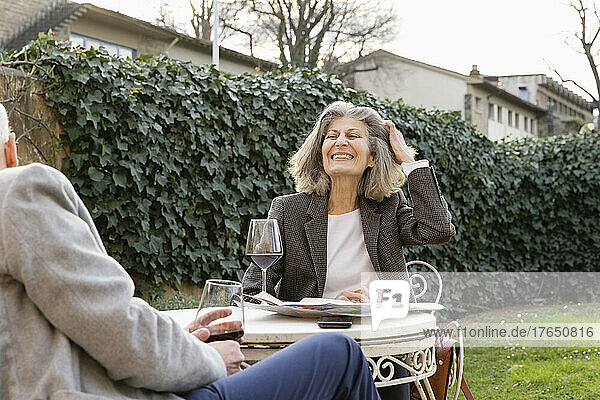 Happy senior couple with wineglasses sitting in hotel garden