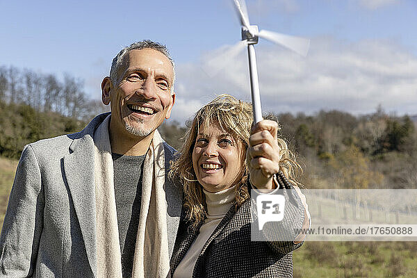 Happy mature couple looking at wind turbine model