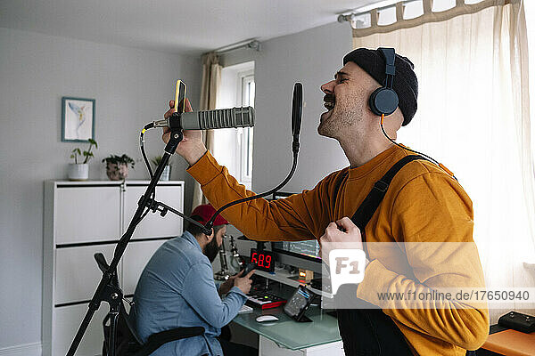 Freiberufler mit Mikrofon und Mobiltelefon  der im Heimstudio singt