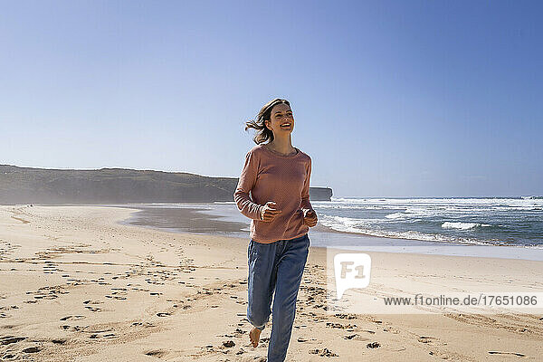 Happy woman running at beach on sunny day
