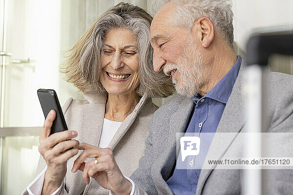 Happy senior woman sharing smart phone with man
