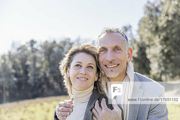 Smiling mature couple day dreaming on sunny day