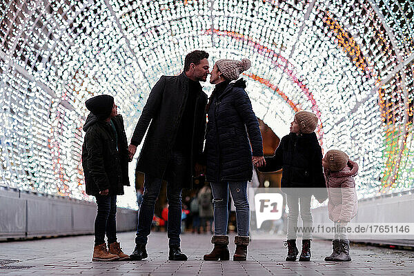 Siblings looking at parents embracing each other in illuminated tunnel