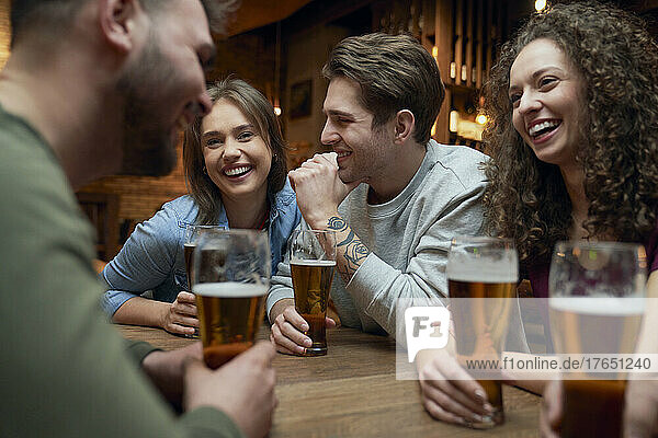 Group of happy friends having beer and socializing in a pub