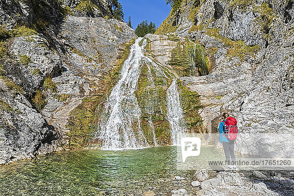 Female hiker admiring Glasbach Waterfall in Bavarian Prealps