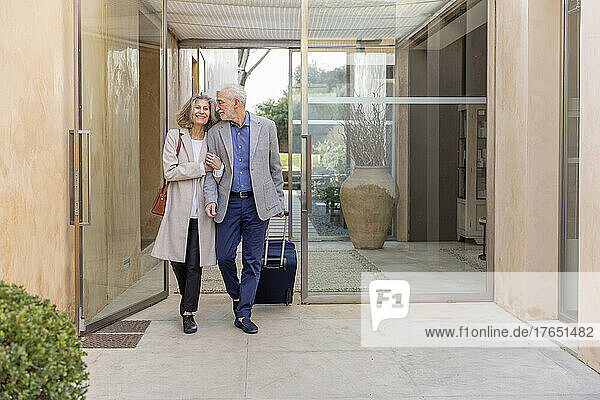 Smiling senior couple walking in lobby at boutique hotel