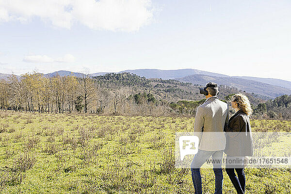 Mature couple admiring mountains and trees on sunny day
