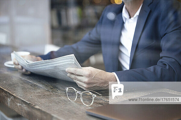Businessman with newspaper sitting at table in cafe