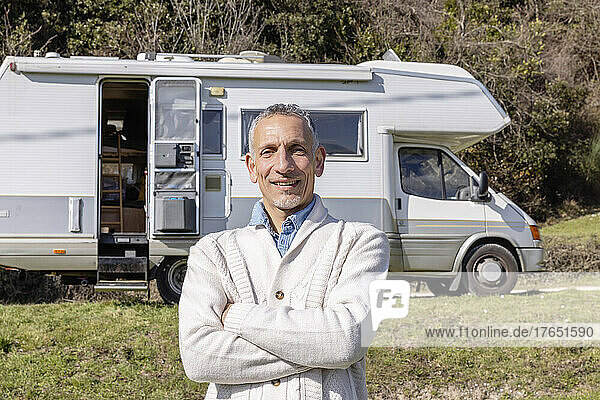 Confident man with arms crossed in front of motor home